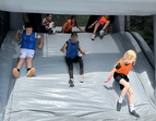Geschafft! – Mit voller Energie rutschen die Kinder ins Ziel und feiern ihren Teamerfolg auf der aufblasbaren Riesenrutsche.